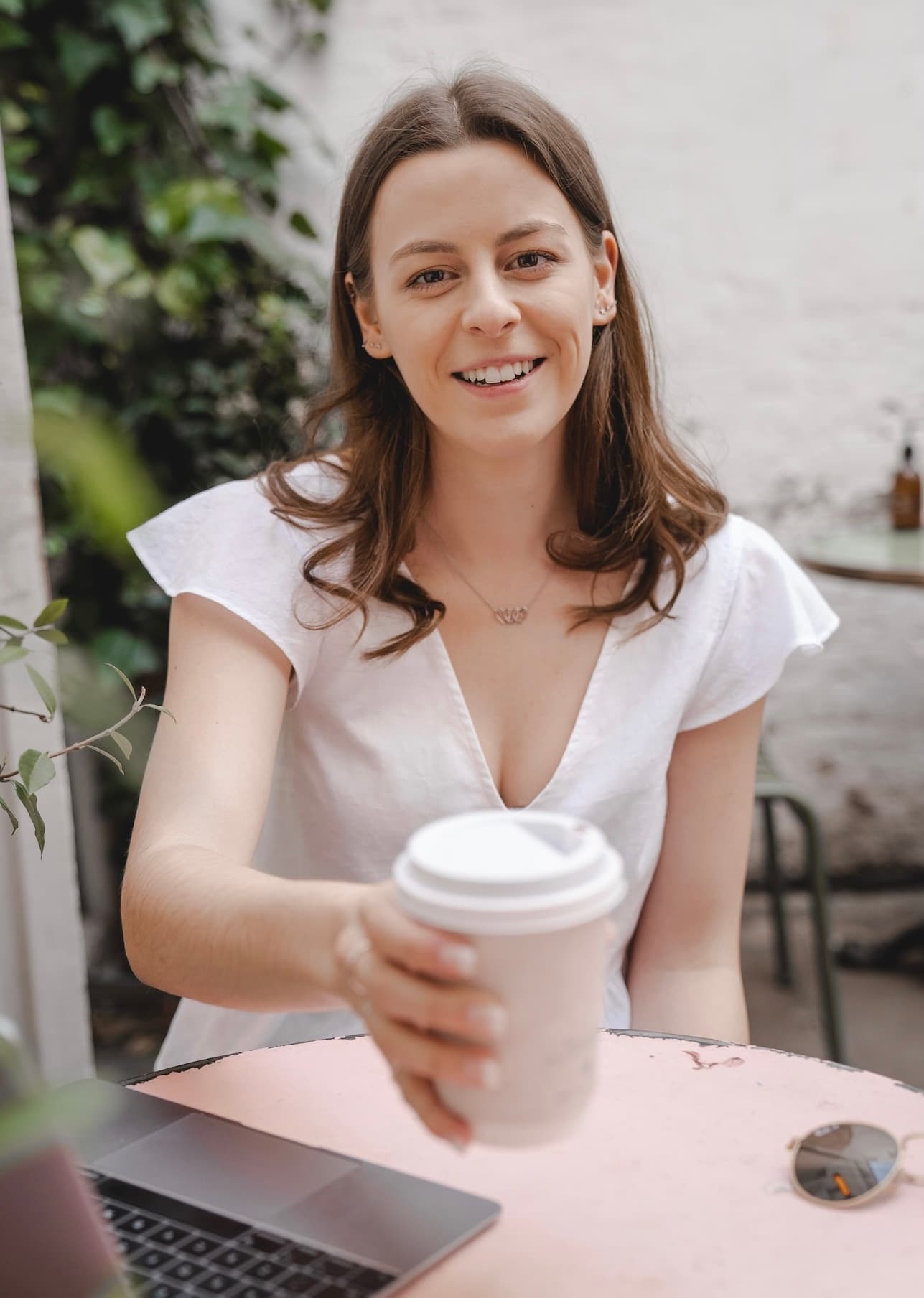 Sofia in a cafe holding up a takeaway coffee cup